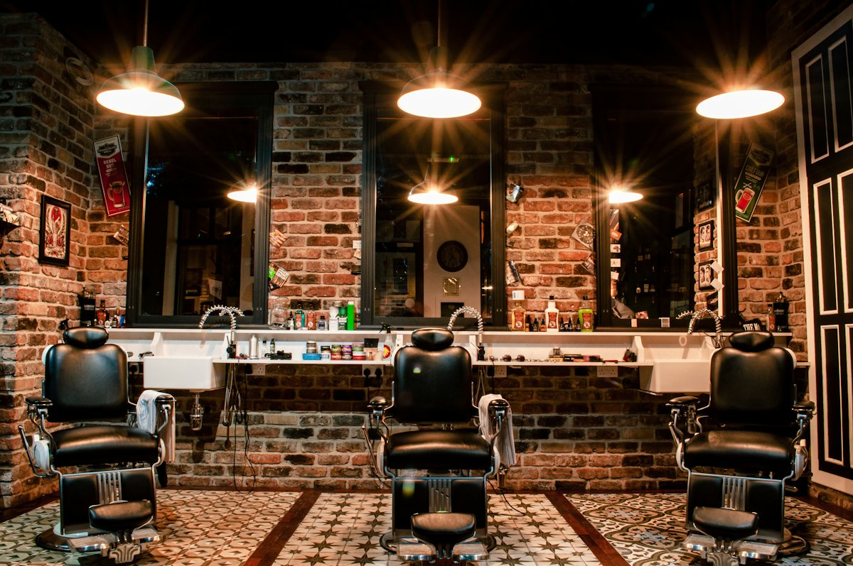 A black leather barber chair in front of a brick wall